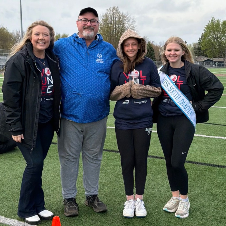 MaKayla smiling with a young person on an outdoor sports field